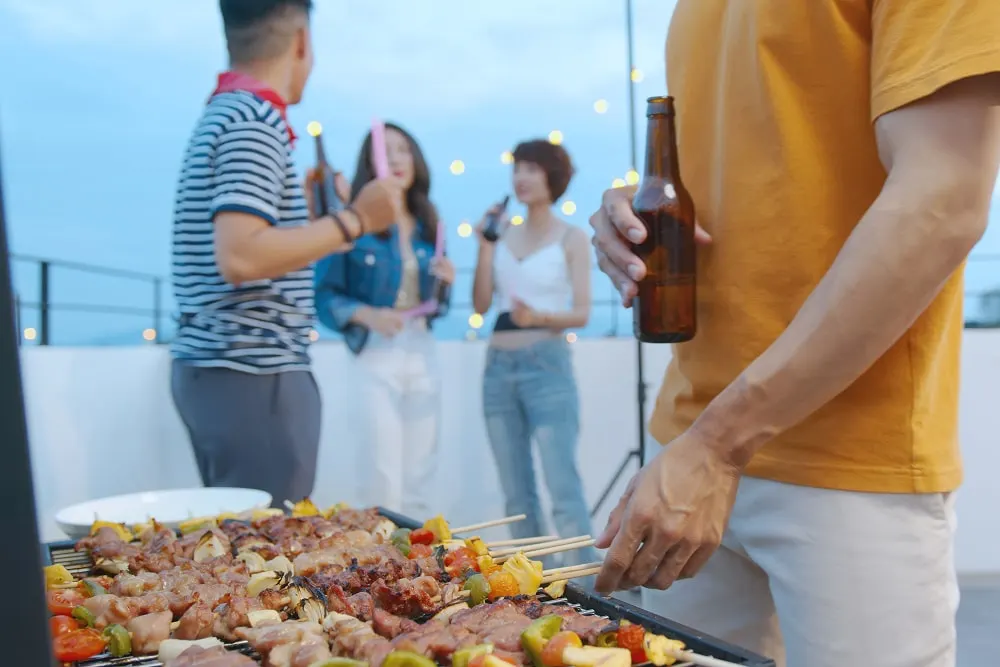 happy-asian-man-with-friends-barbecue-dinner-party-enjoying-meal-together-min.webp